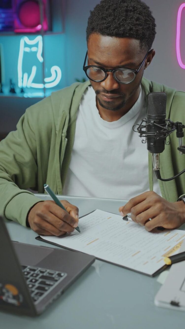 Artist reading over music contract terms and taking notes in front of a podcast mic
