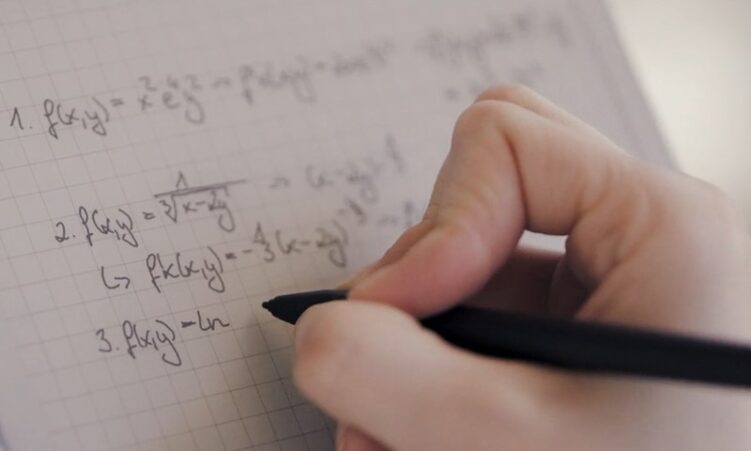 A person writes in a notebook with a pen